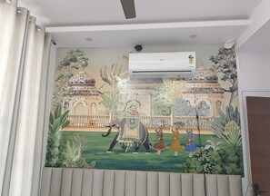 Et mural med traditionel arkitektur, en hest og mennesker i en gårdhave.