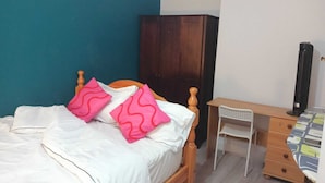Een slaapkamer met een bed, een bureau, een kast en een radiator.