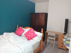 A bedroom with a bed, a desk, a wardrobe, and a radiator. - Entire Nuneaton Home Sleeps up to 6 Guests Near Town and George Eliot Hospital (Nuneaton)