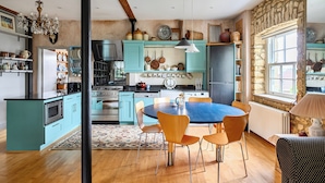 Una cocina con gabinetes color turquesa, una mesa de comedor con sillas y un candelabro.