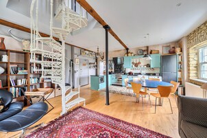 Un amplio salón con una escalera, una mesa de comedor y una cocina al fondo.