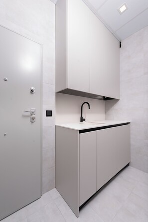 Eine moderne Küche mit weißen Schränken, einem schwarzen Wasserhahn und einer Deckeneinbaustrahlungsleuchte.