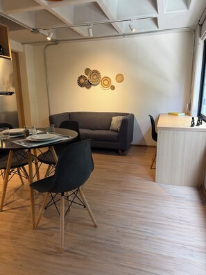A modern interior with a dining area, a sofa, and a wall with decorative plates. - Modern 1BR in Juárez with fast WiFi, great natural light, a comfortable king bed, a fully equipped kitchen, and a luxury bathroom. Perfect for couples or solo travelers seeking comfort, style, and a prime location in Mexico City. (Cuauhtémoc)