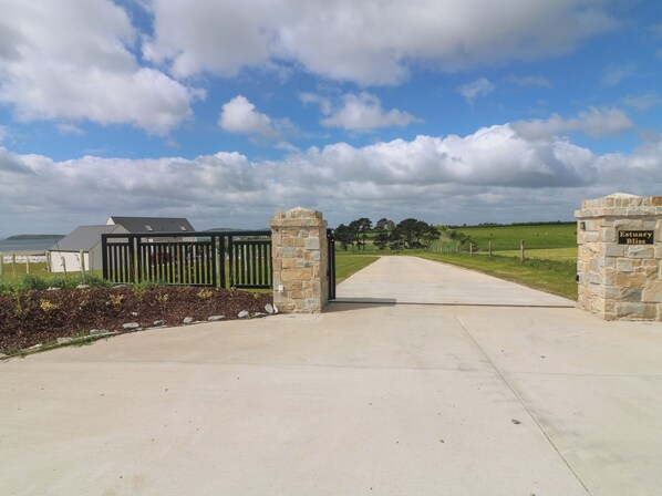 A gated entrance with a stone wall and a sign reading 'Estuary Bliss.'