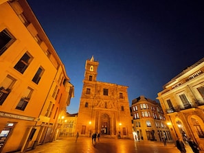 A historic building with a prominent tower and arched windows, surrounded by other buildings.