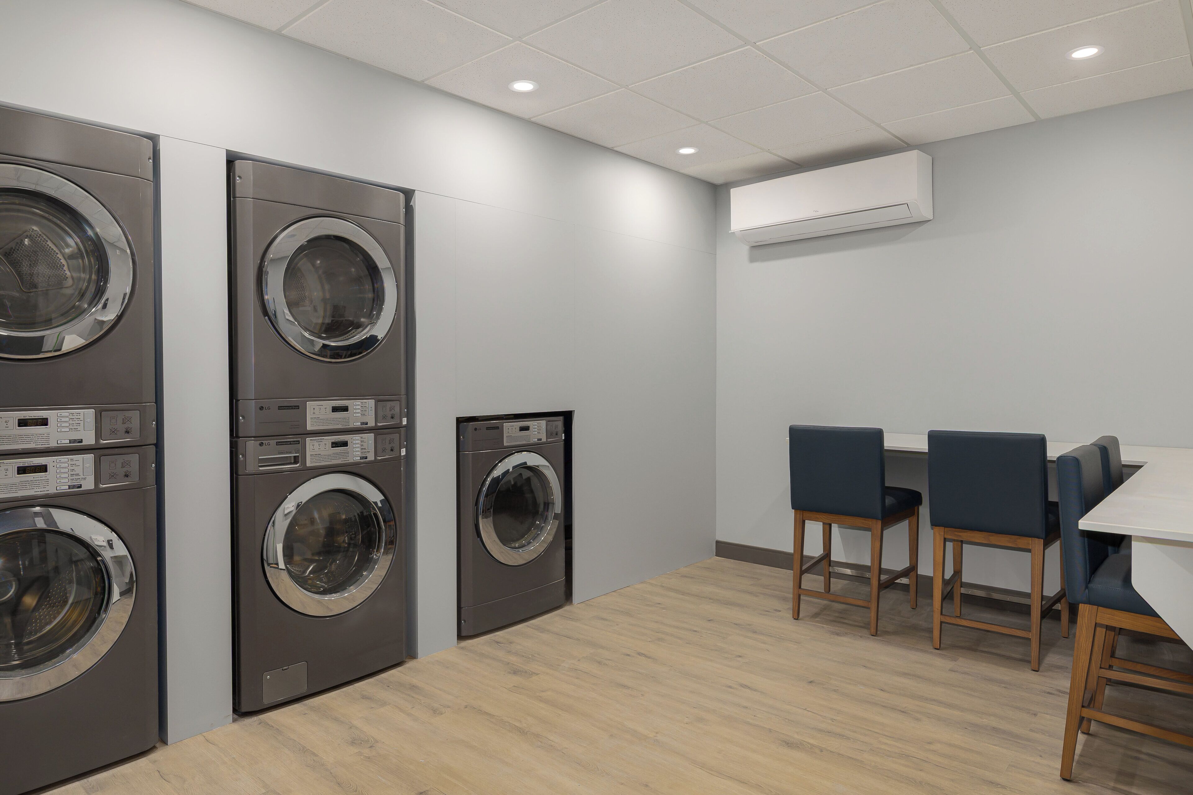 A laundry room with multiple washing machines, a table, and chairs.