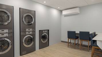A laundry room with multiple washing machines, a table, and chairs.