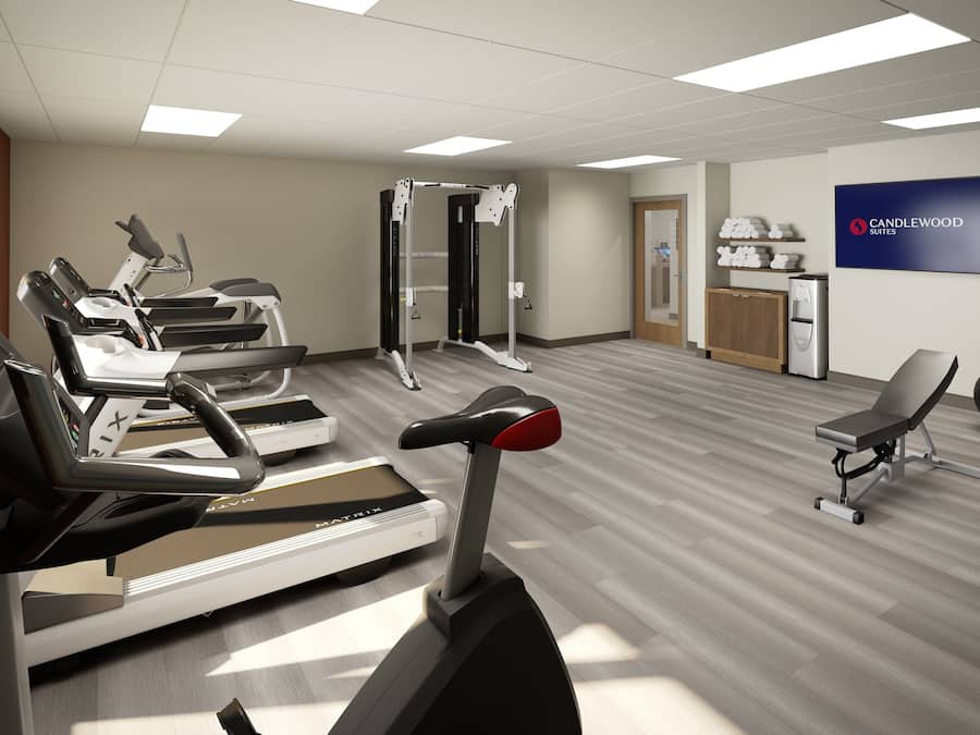 Een fitnessruimte met loopbanden, een krachtapparaat en een bord met daarop Candlewood Suites.