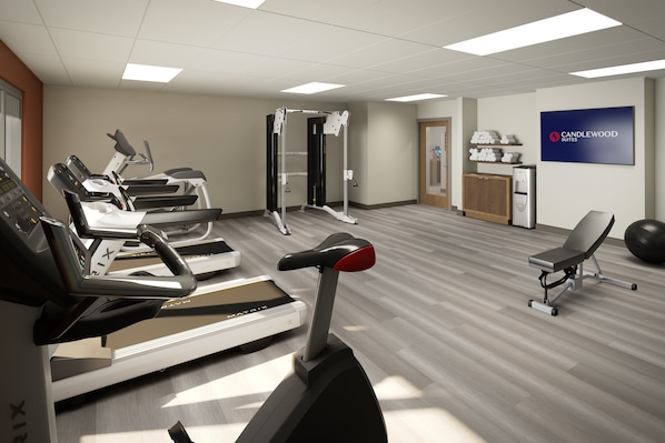 A fitness center with treadmills, a weight machine, and a wall-mounted sign for Candlewood Suites.