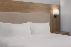 Una cama bien hecha con sábanas blancas y cabecera de madera.