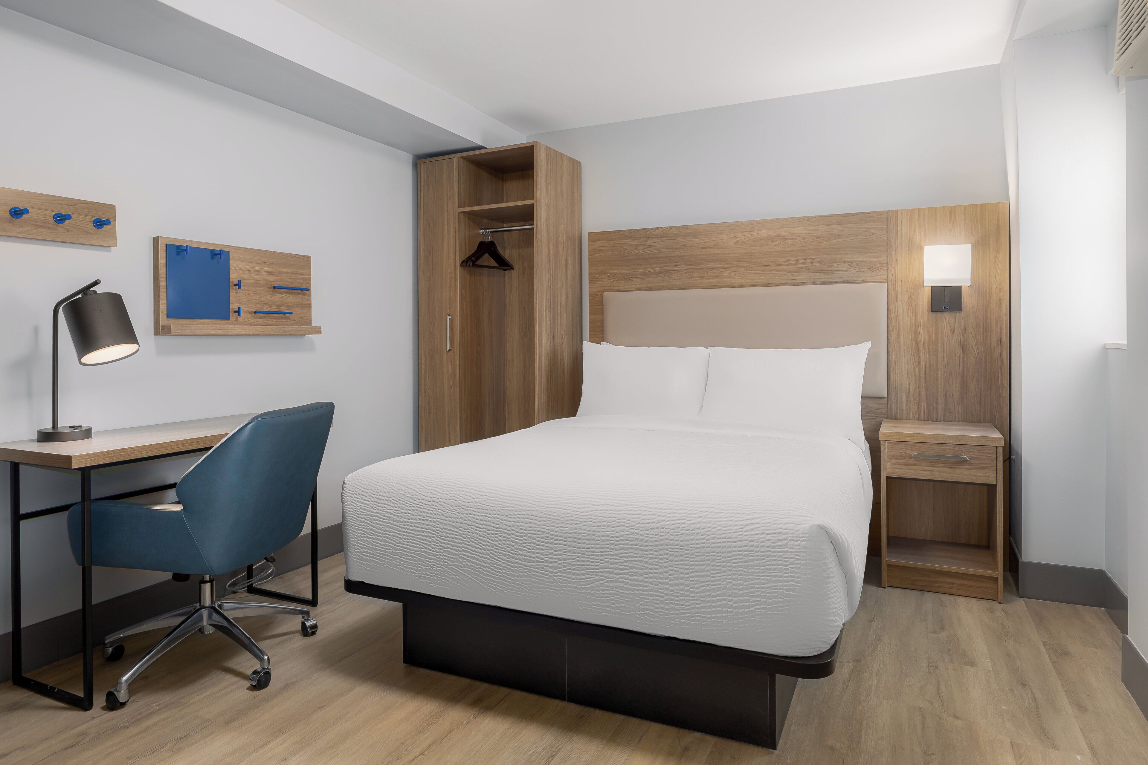 A hotel room with a bed, desk, chair, and bedside tables.