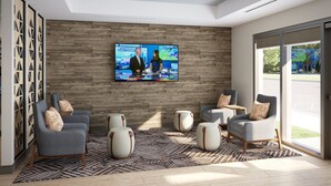Um lobby moderno com uma televisão grande, assentos confortáveis e uma parede de madeira.