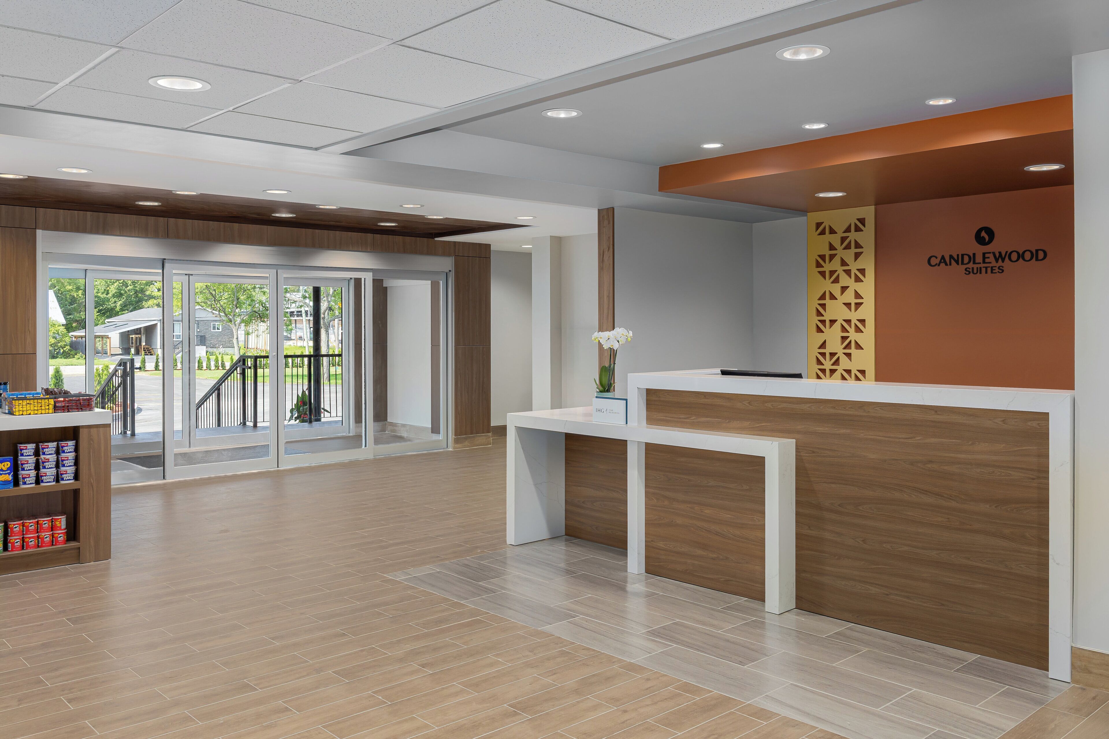 A reception area with a modern design, including a reception desk, a glass door entrance, and a wooden floor.