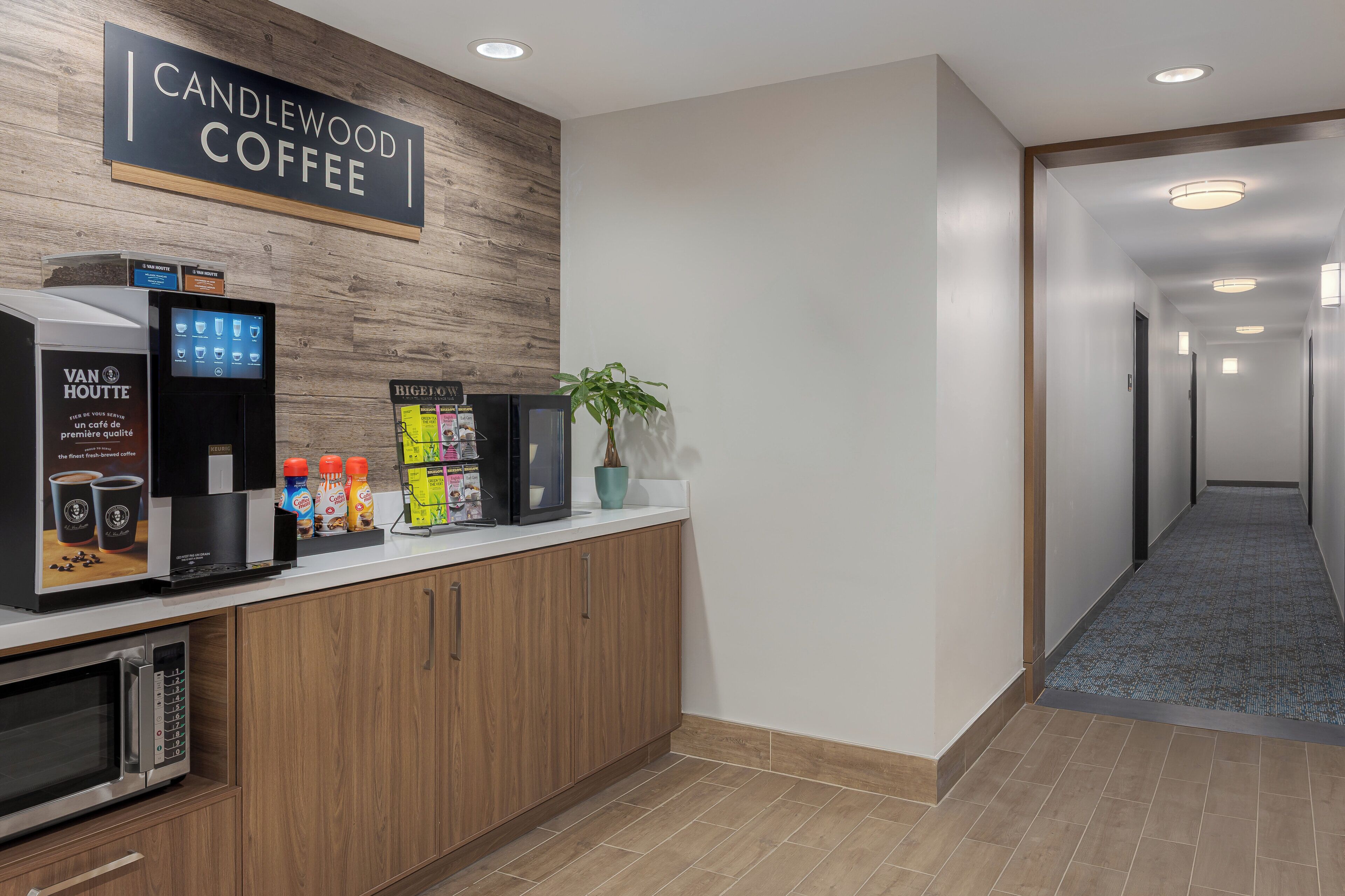 A coffee station with a sign that reads 'CANDLEWOOD COFFEE,' a coffee machine, and various coffee products.