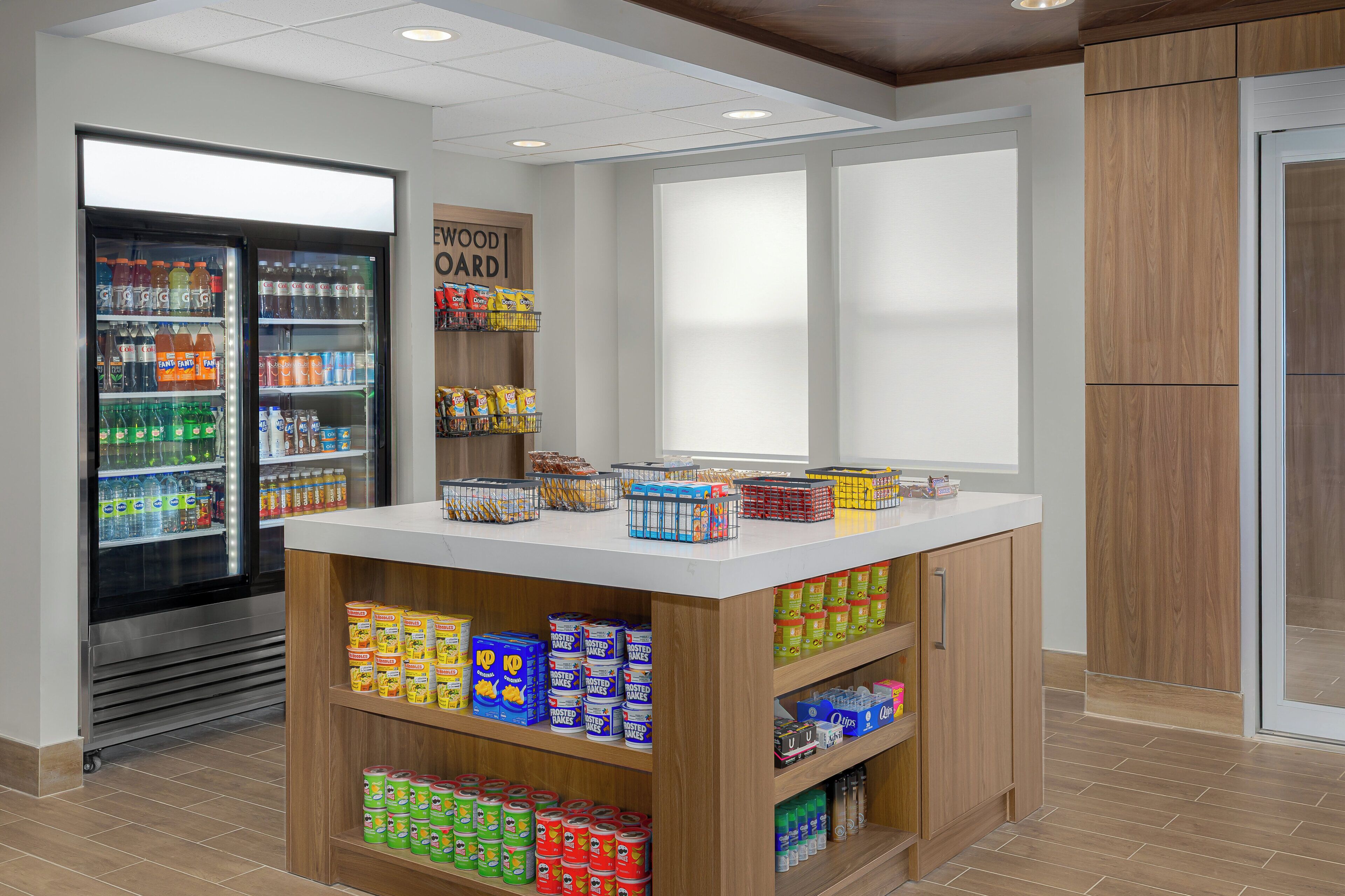 A beverage vending machine stocked with various drinks, a snack bar with chips and cereal, and a wooden counter with packaged goods.