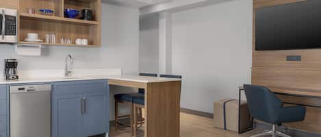 Une cuisine moderne équipée d’un lave-vaisselle, d’une machine à café et d’un meuble en bois contenant de la vaisselle.