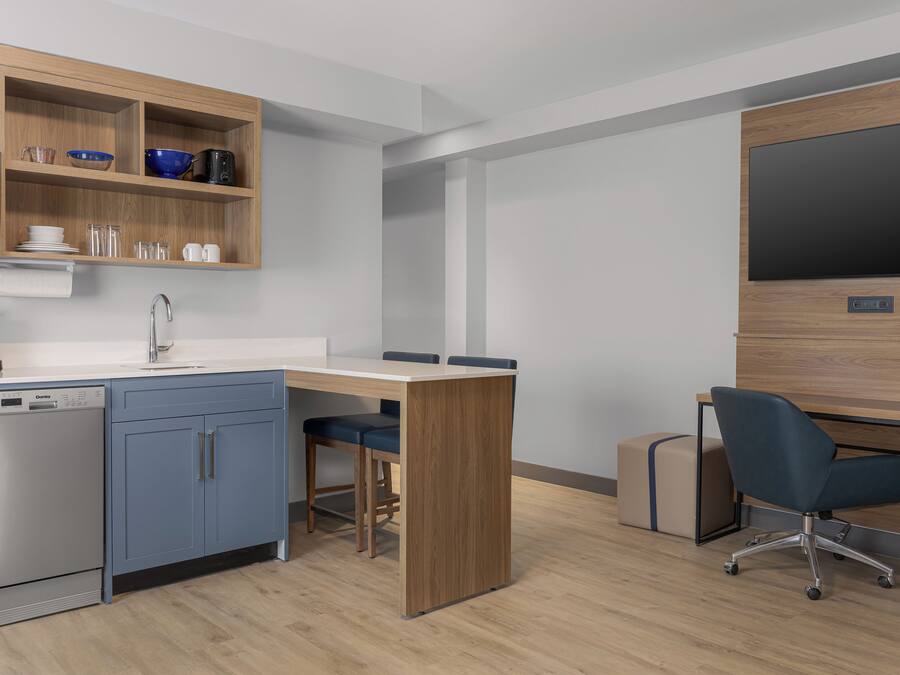 A modern kitchen with a dishwasher, a coffee maker, and a wooden cabinet with dishes.