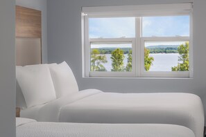 Un dormitorio con un ventanal que ofrece vistas a un lago y árboles.