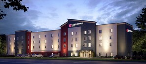 Un hotel de varios pisos con un diseño moderno, que destaca un letrero prominente de 'CANDLEWOOD SUITES'.