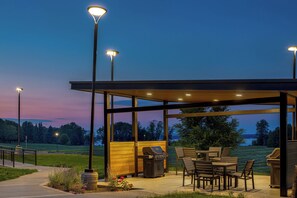An outdoor patio with a grill, seating, and street lamps.