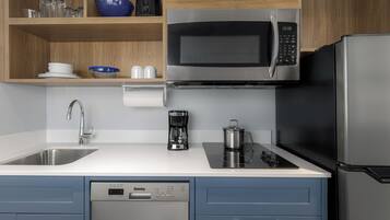Une cuisine moderne équipée d’un four à micro-ondes en acier inoxydable, d’une machine à café et d’un lave-vaisselle.