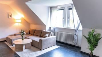 A modern living room with a sofa, a small round table, and a potted plant.