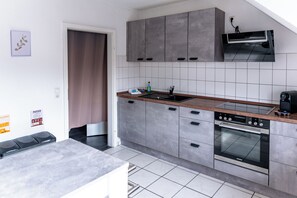 Cocina moderna con armarios grises, encimera de madera, horno empotrado y microondas de pared.