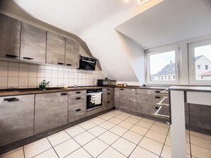 Eine moderne Küche mit grauen Schränken, einem eingebauten Ofen und einem Fenster mit Blick auf eine Wohngegend.