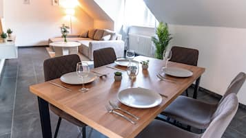 Een eetgedeelte met een houten tafel gedekt voor vier personen, inclusief borden, bestek en glazen.