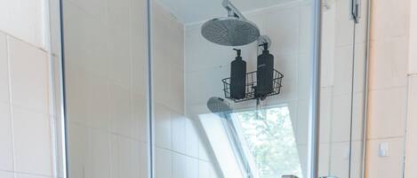 A glass-enclosed shower with a handheld showerhead and a wall-mounted faucet.