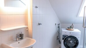 A modern bathroom with a white sink, wooden cabinet, and a washing machine. - Premium City Apartment (Braunschweig)