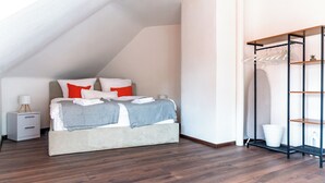 A bedroom with a bed, a nightstand, a hanging clothes rack, and a white wall. - Premium City Apartment (Braunschweig)