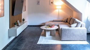 A modern living room with a sofa, a coffee table, a TV, and a lamp. - Premium City Apartment (Braunschweig)