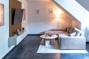 A modern living room with a sofa, a coffee table, a TV, and a lamp. - Premium City Apartment (Braunschweig)