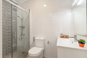 Une salle de bain équipée d’une douche, de toilettes, d’un lavabo et d’un miroir.