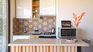 Una cocina con microondas, cafetera y un jarrón decorativo con flores naranjas.