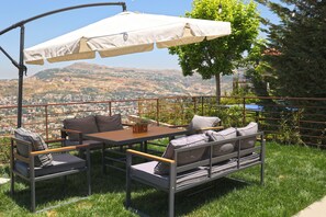 Un área de estar al aire libre con mesa y sillas, un toldo y vistas a un paisaje montañoso.