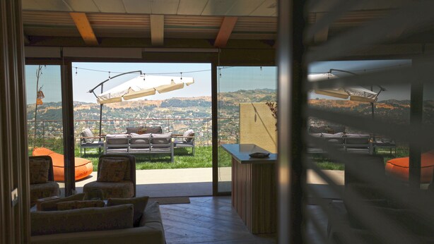 Un interior moderno con vistas a una colina, techo de madera y zona de estar exterior.