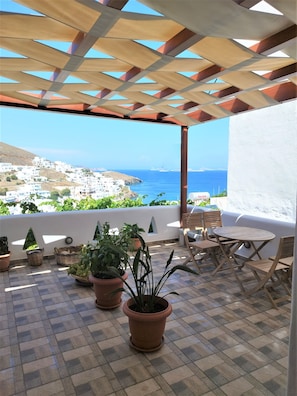 A terrace with a view of the sea, potted plants, and outdoor furniture. - Primrose Apartments  (Astypalaia)