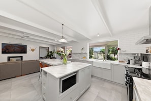 A modern kitchen with white cabinetry, a central island, and a large window offering a view.