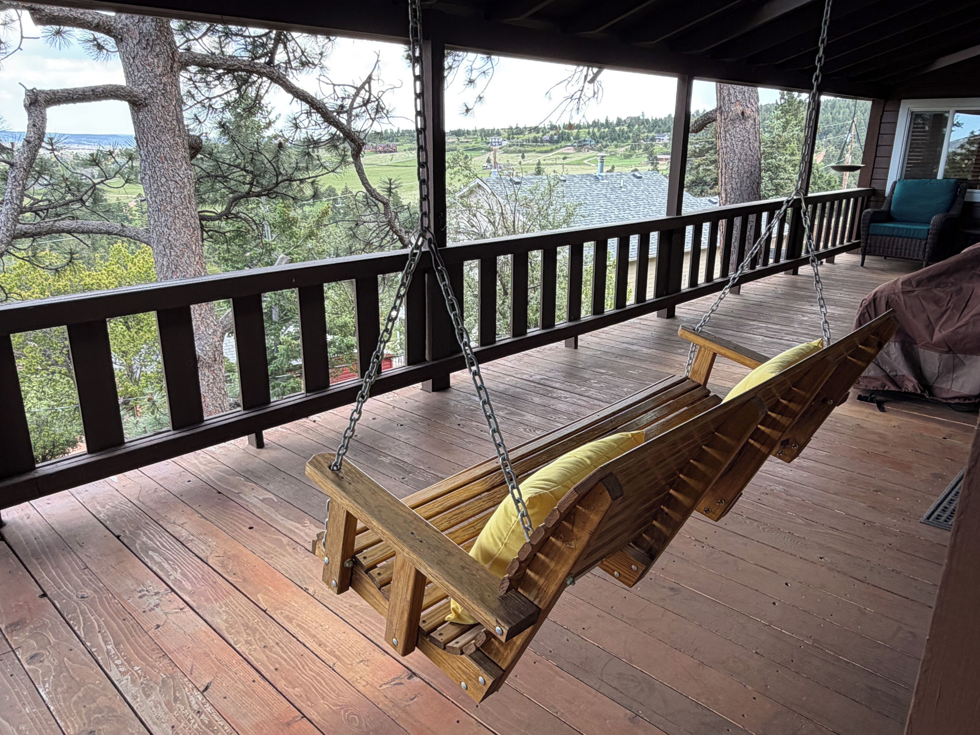 A wooden swing chair on a porch with a view of a green landscape.. Built in 1908 this historic cabin is full of original charm with a penthouse view. Step inside and you are immediately greeted by a full unobstructed view of Elephant Rock. Sleeping up to 9 people.
