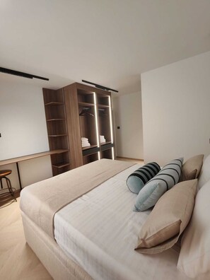Ein modernes Schlafzimmer mit einem großen Bett, einem Kleiderschrank und einem Schreibtisch.