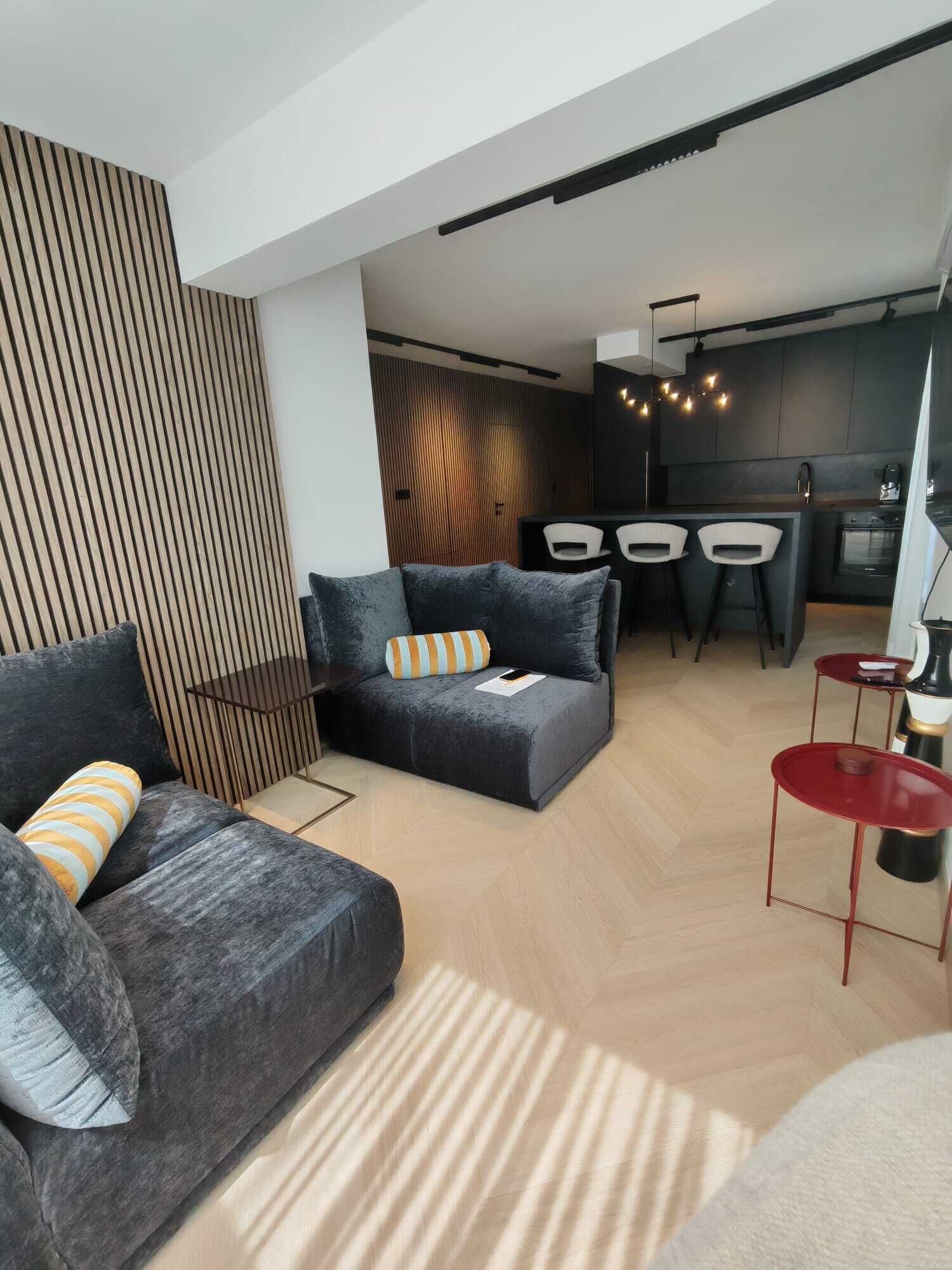 Una sala de estar moderna con un sofá, una mesa de centro y un comedor con sillas, con una cocina al fondo.