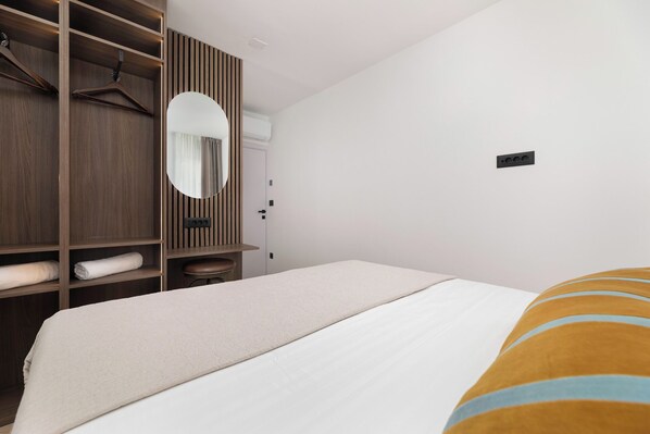 A bedroom with a bed, a wardrobe, a mirror, and a door. - AUREA RESIDENCE BAŠKA (Baška)