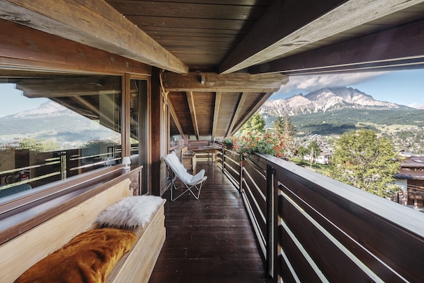 Ein Balkon mit Holzbalken, einer gepolsterten Bank und Blick auf einen Berg.