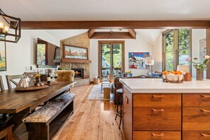 A spacious kitchen with wooden flooring, a large island, and a dining area with a bench. - Luxury in Old Town | Hot Tub | Walk to Main St (Park City)