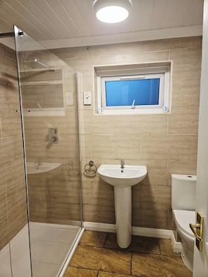 A bathroom with a glass shower enclosure, a pedestal sink, and a toilet. - Cozy Egremont Apartment With Free Parking & Wifi (Egremont)
