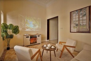 Ein Wohnzimmer mit Kamin, Projektionsfläche und einem Gemälde an der Wand.