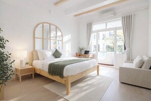 Ein Schlafzimmer mit Bett, Nachttisch, Lampe und Blick ins Freie.