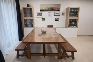 Ein Essbereich mit einem Holztisch und Bänken, umgeben von Schränken mit Glastüren.